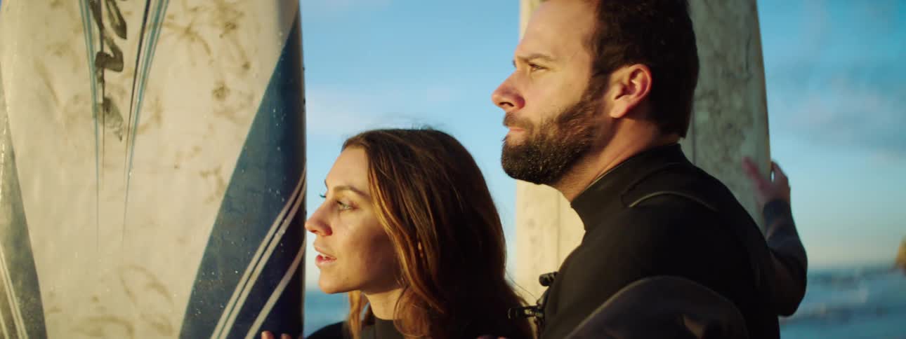 A man and woman are surfing on the ocean