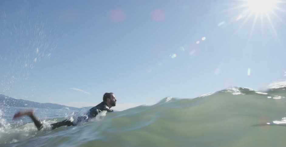 A man paddling his surf board out in to the ocean