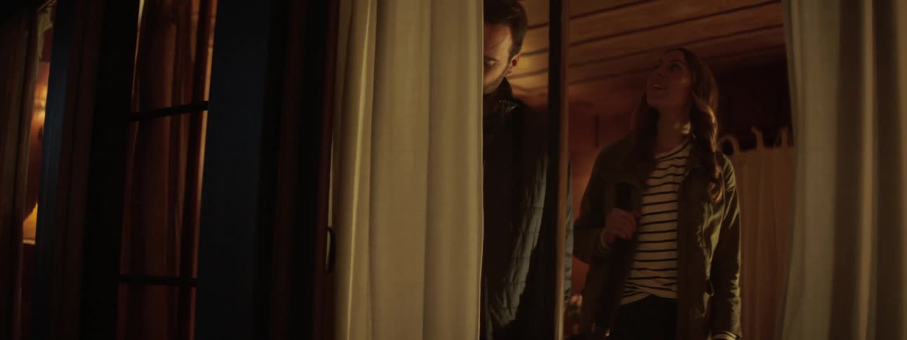 A man opens the front door of his home for a woman and they walk inside and hug