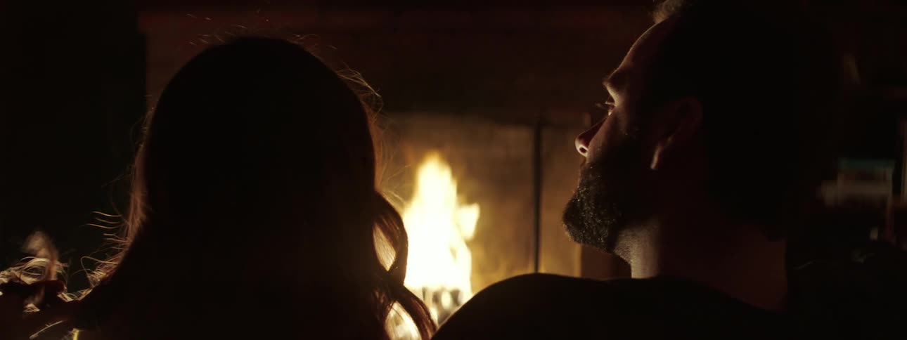 Silhouette of young couple sitting in front of the flames in the fireplace