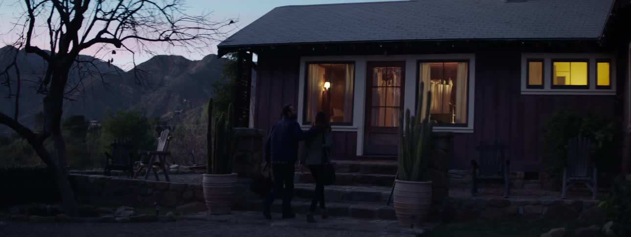 Couple gets out of a car and walks to the entrance of a house at sunset