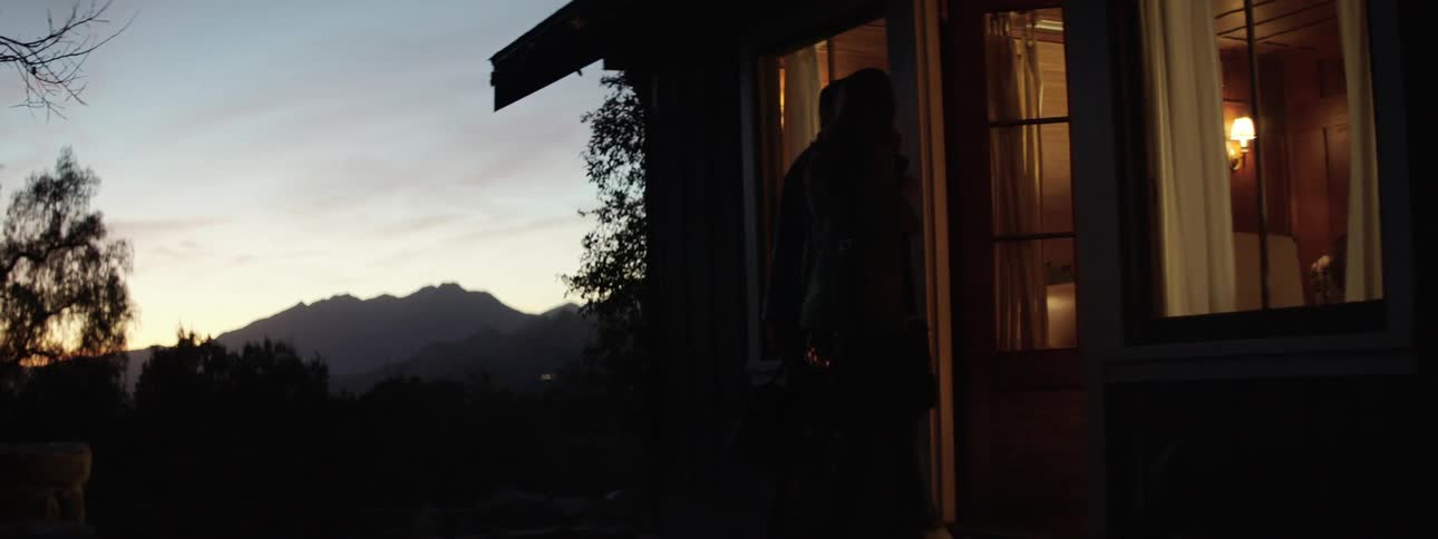 A man and woman walk in to their home at night