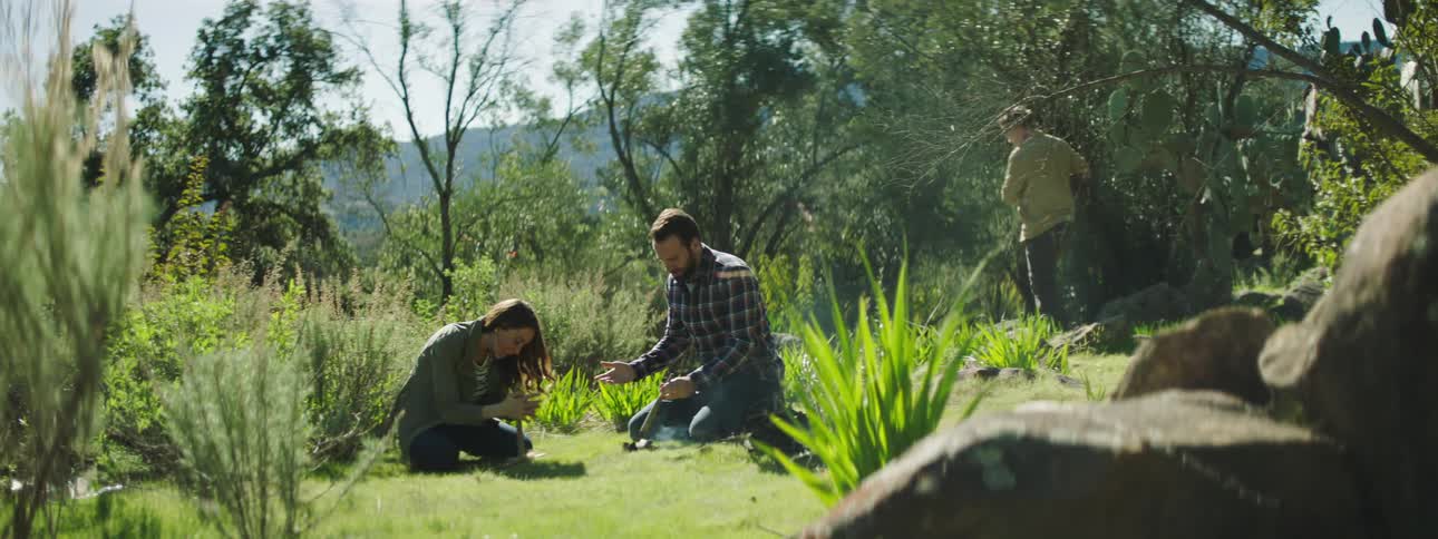 Young couple trying to light a friction fire in the wilderness near the mountains