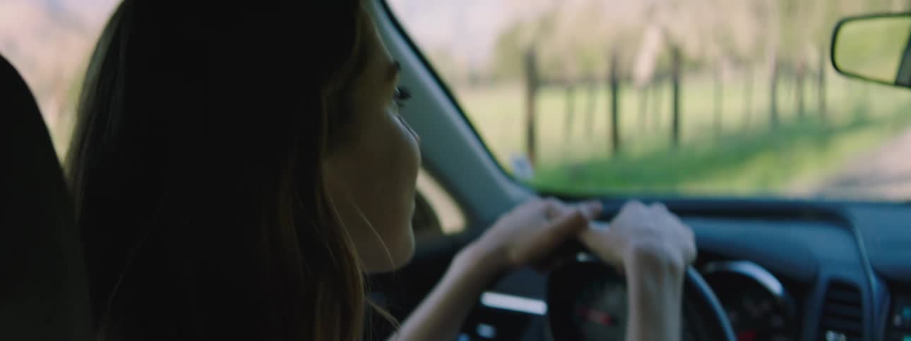Woman with brown hair talks to her friend while driving a car