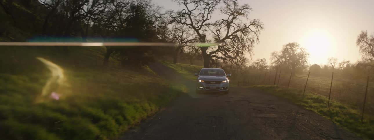 A car travels on a rural road at sunset