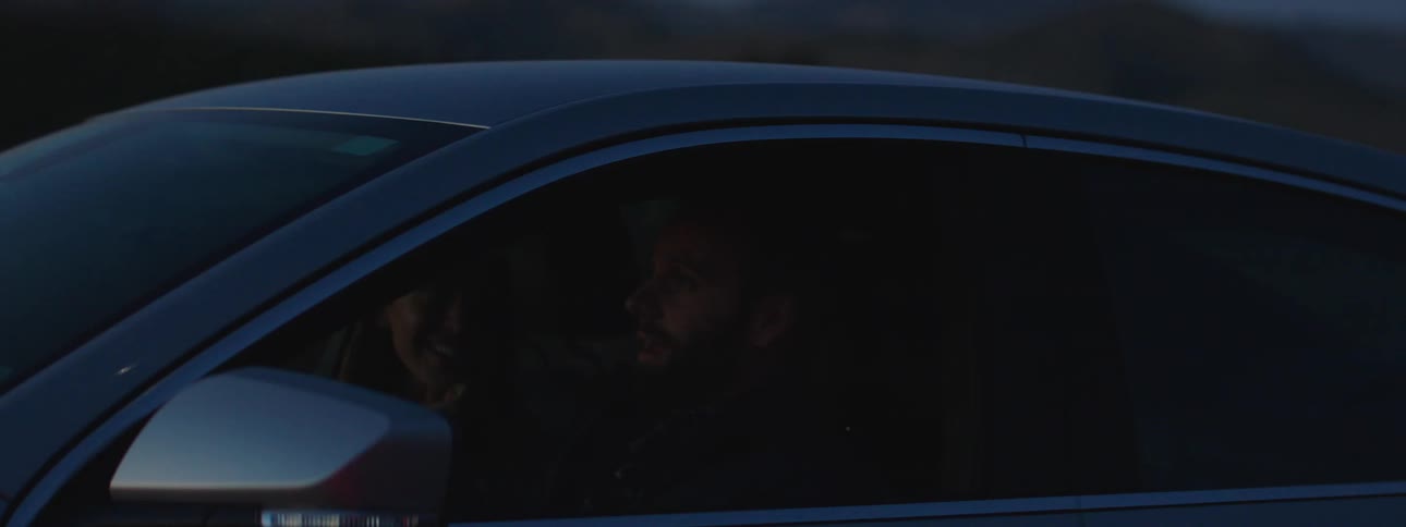 A man and a woman driving in a car and talking