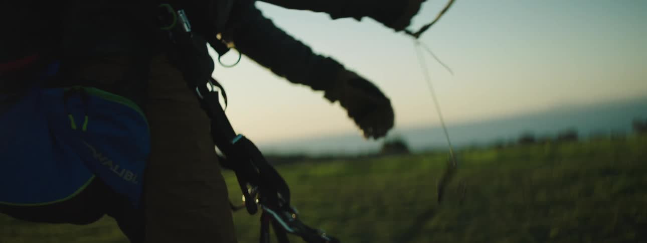 Man standing on the top of a hill at morning checks parachute gear