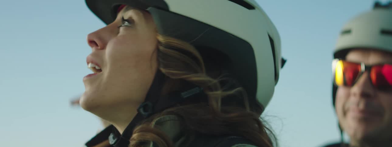 A man and woman wearing helmets talk