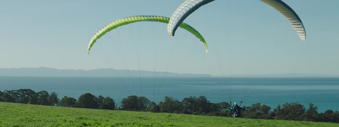 People parasailing with jackets and helmets with the sky in the background