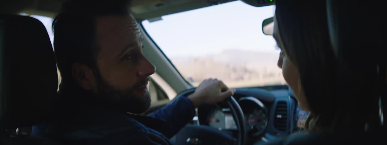Man and woman converse while riding in car through countryside