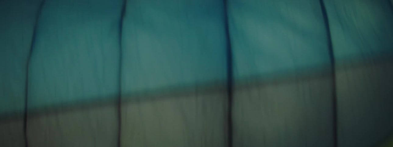 A man holds on to a parachute as it blows in the wind