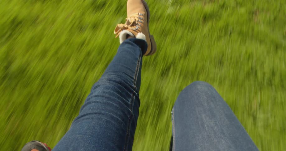 Woman flying on a parachute lands on a grass plain