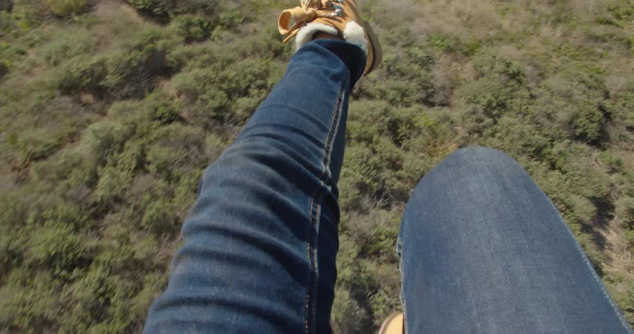 A person kicks their legs as they hover and move over a field