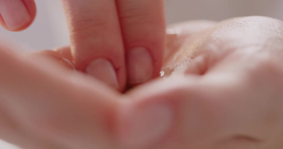 A person rubbing oil in the palm of their hand