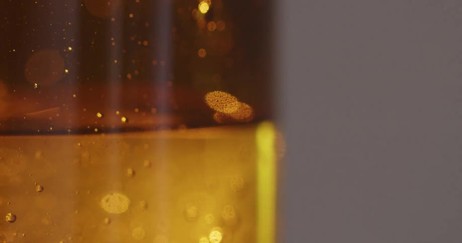 Bubbles form in a glass of gold liquid and gel
