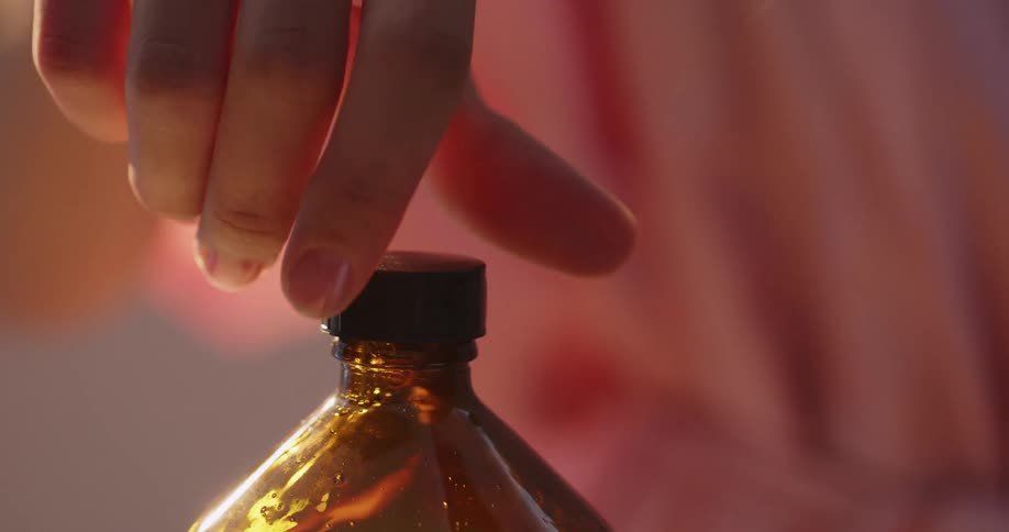 Close up of a hand unscrewing a cap on bottle