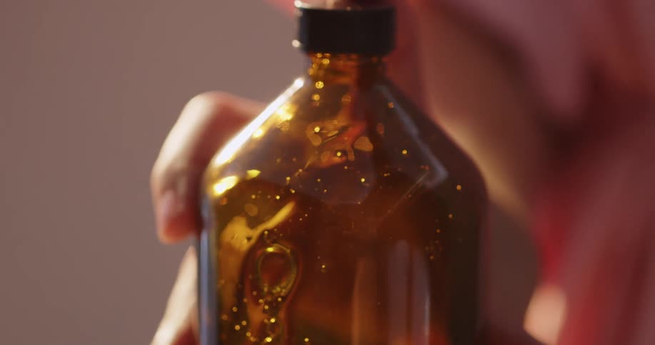 Woman picks up a bottle filled with honey and turns it upside down