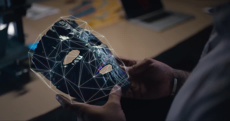 A man picks up a futuristic electronic mask from a table