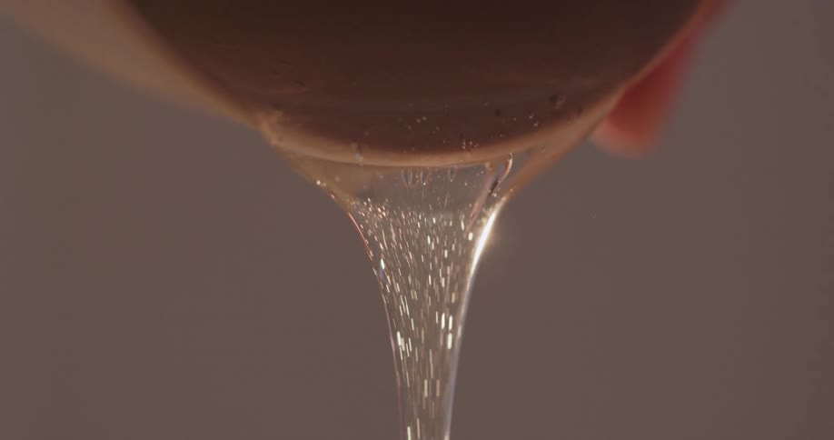 A person pouring honey out of a container