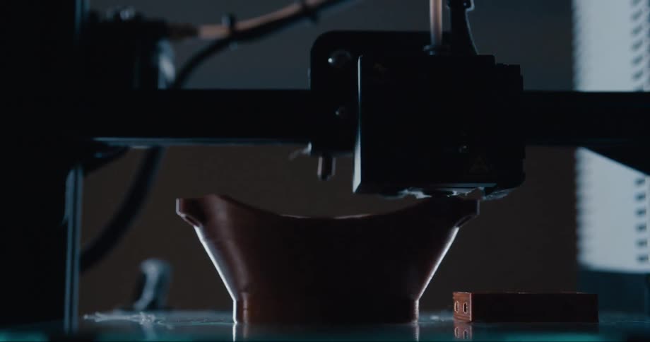 The head of a 3d printer sweeps back and forth as it deposits more plastic to create an object