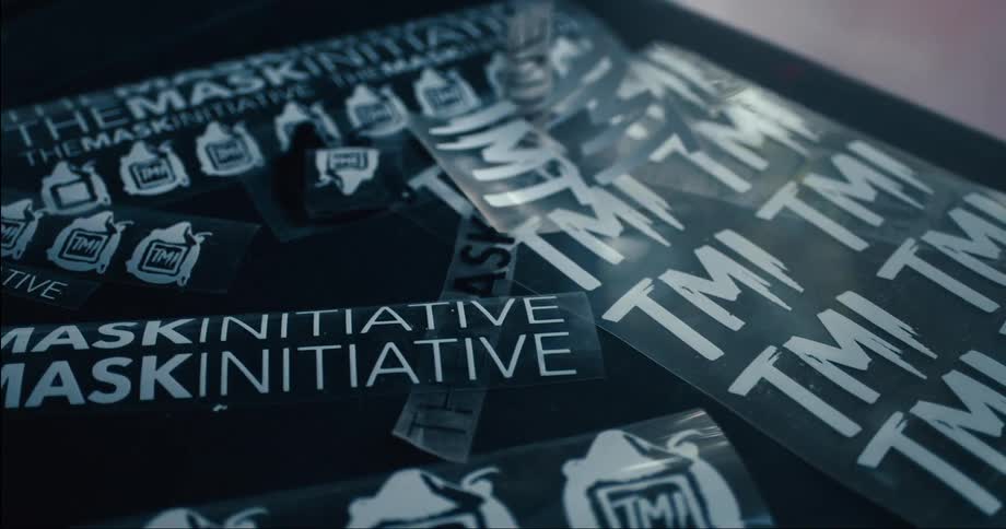 Signs and badges referencing a mask initiative lay on flat surface
