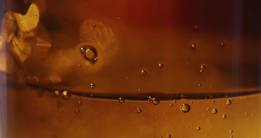 Close up of a hand picking up a glass jar filled with honey