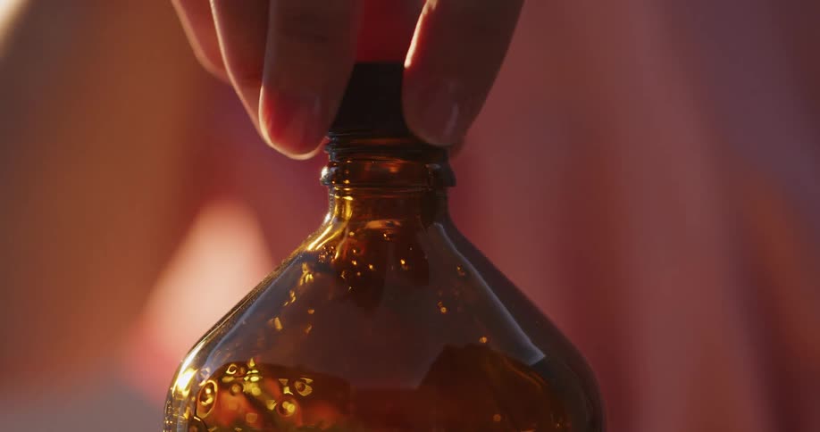 Woman unscrews the black bottle cap from a honey bottle
