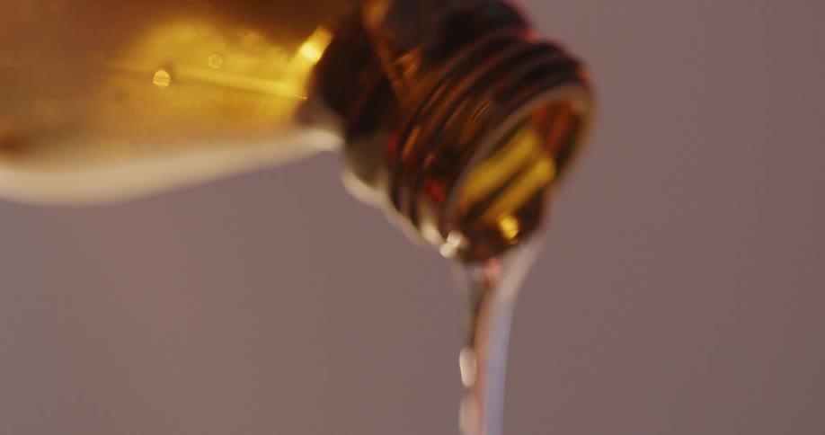 A thick liquid is poured out of an amber colored glass bottle