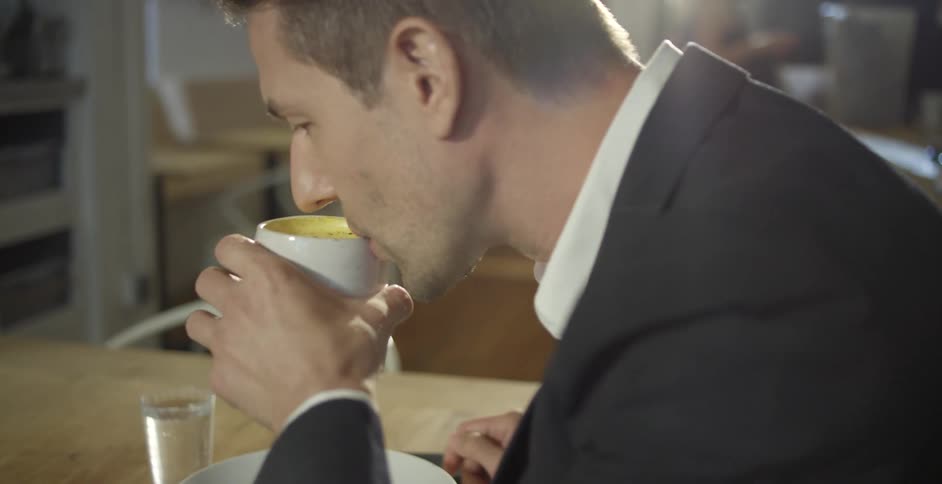 Man in a suit drinks a hot beverage with his breakfast on a restaurant