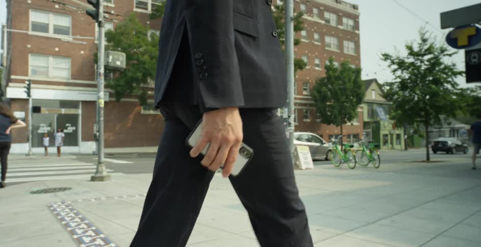 A man crosses the street and walks toward a subway station in a city