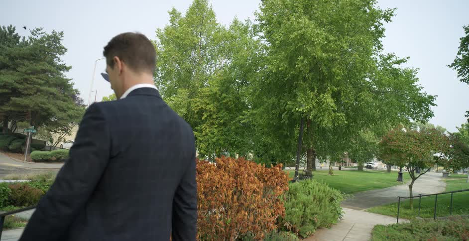 Man with glasses and a suit goes down the stairs in public park