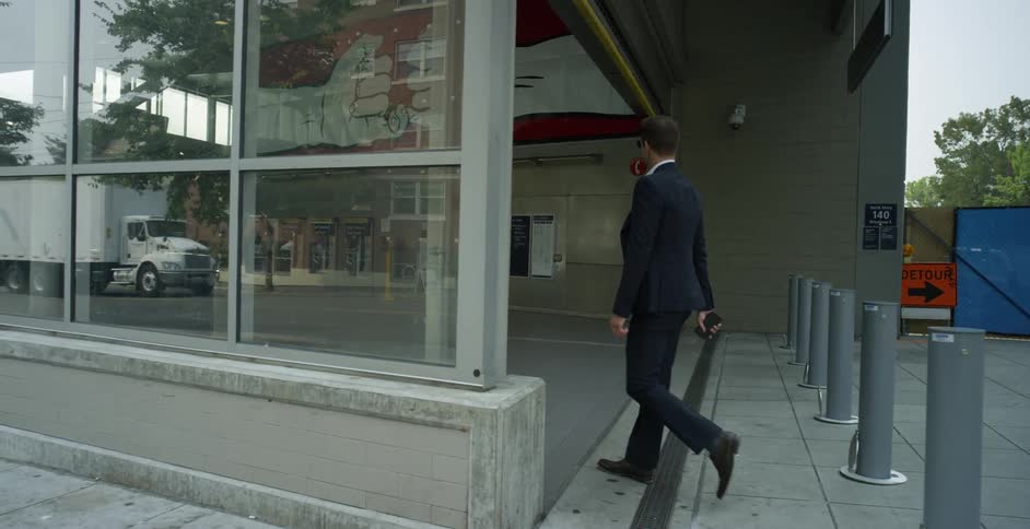Man wearing a suit walking on the sidewalk in the city enters a building