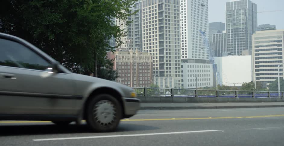 Businessman with a black suit crosses a bridge with tall buildings in the background