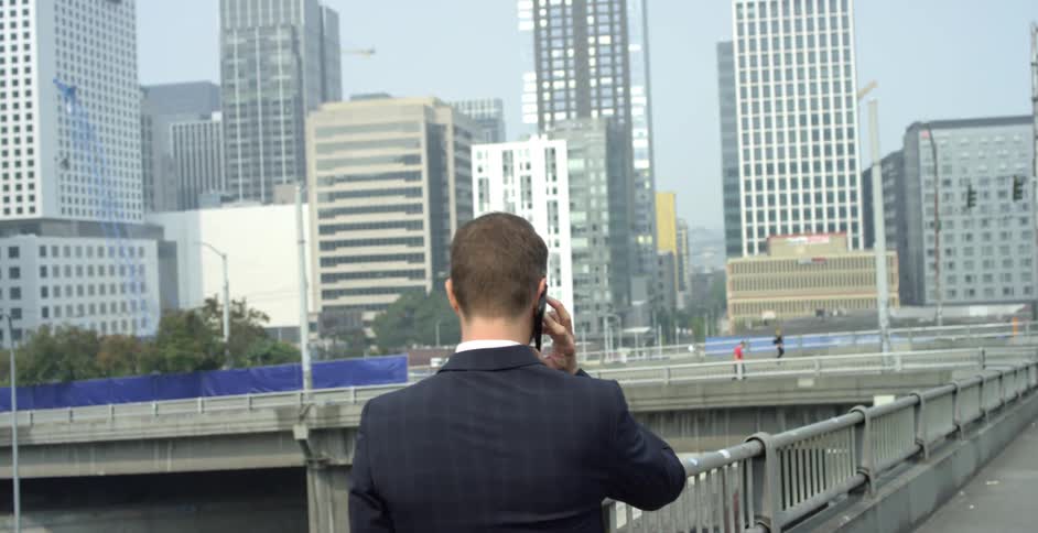 A man talks on his phone while walking in the city