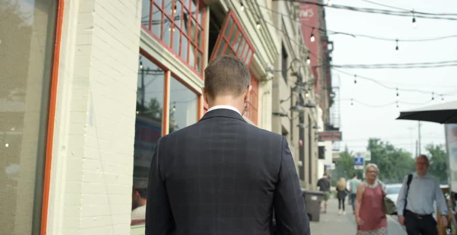 A man in a suit walks down a sidewalk in a metropolis during the day