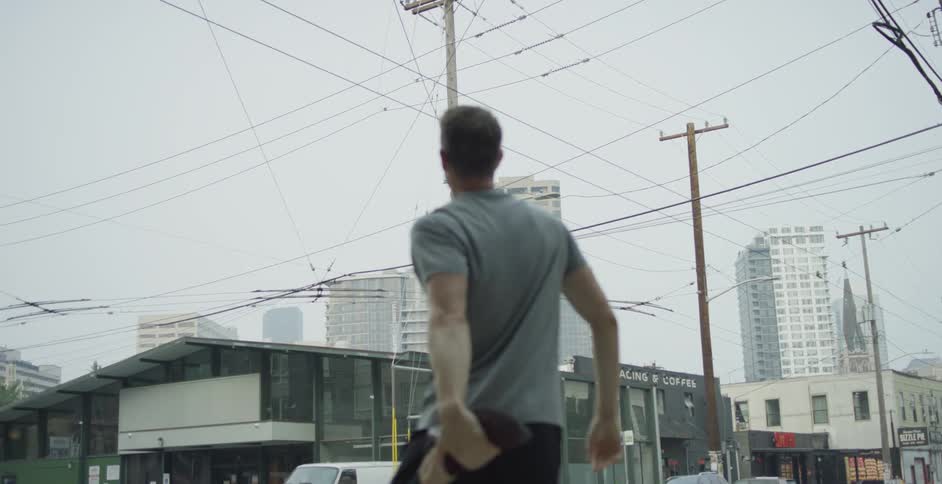 A man does a leg street on a street corner in a metropolis on a cloudy day