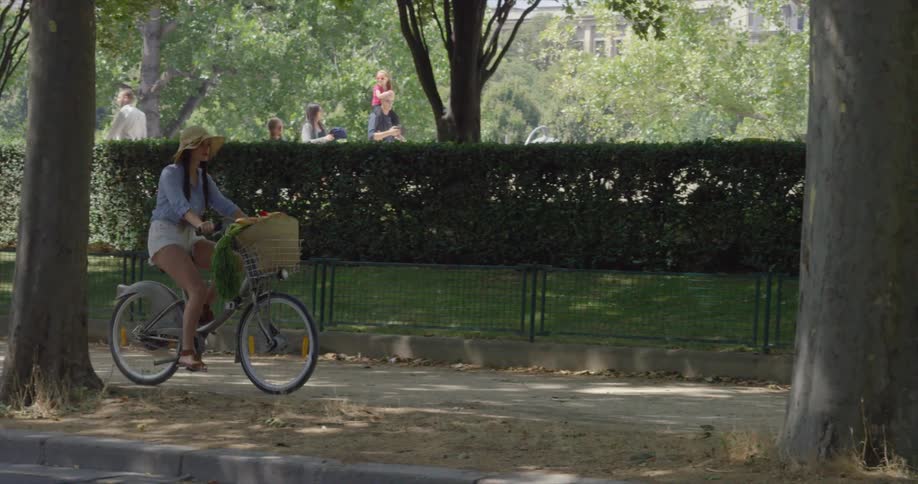 A woman is riding a bike on the sidewalk on a sunny day
