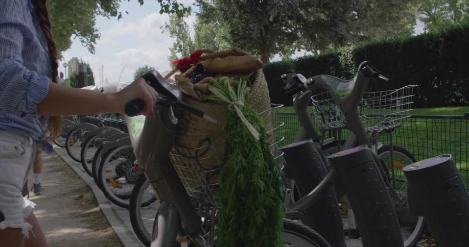A woman is pushing a bike with a basket full of food