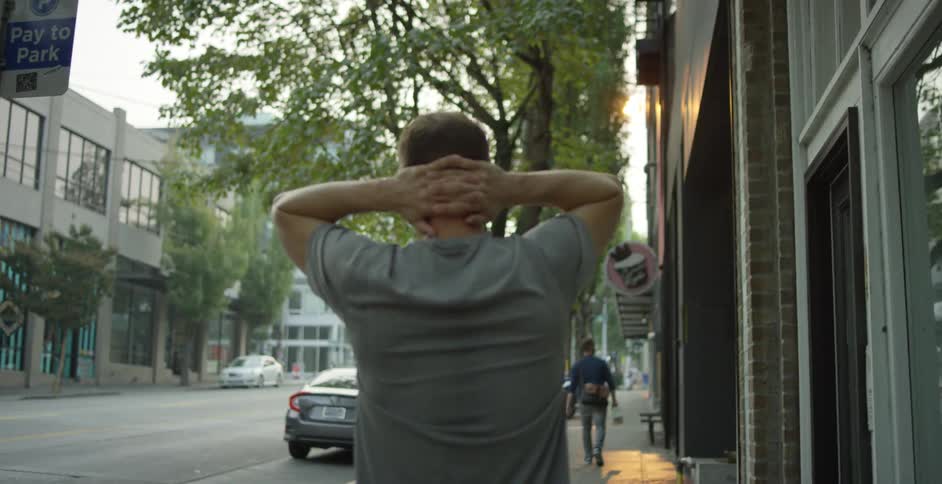 Tired man walking on the sidewalk of a small city at sunset