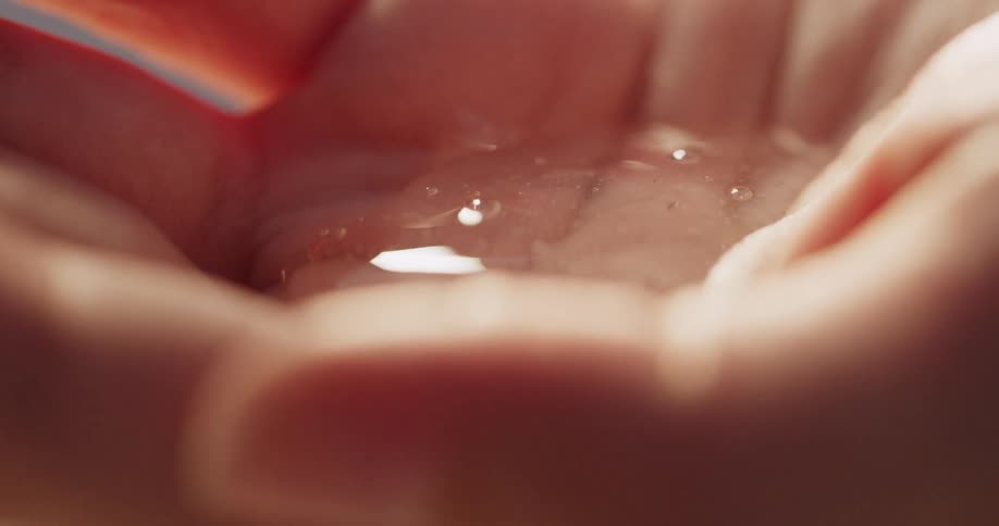 Close up of clear gel squirting on palm and fingers rubbing it in