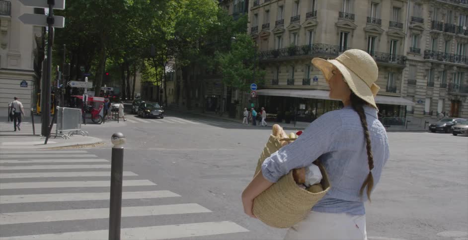People are walking along a city street on a sunny day