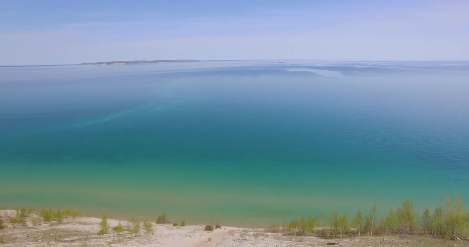 A hilly beach leads to a greenish blue ocean