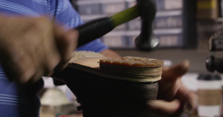 A cobbler attaching a heel to the sole of a boot