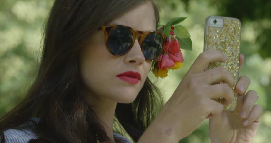A woman is examining her phone on a sunny day