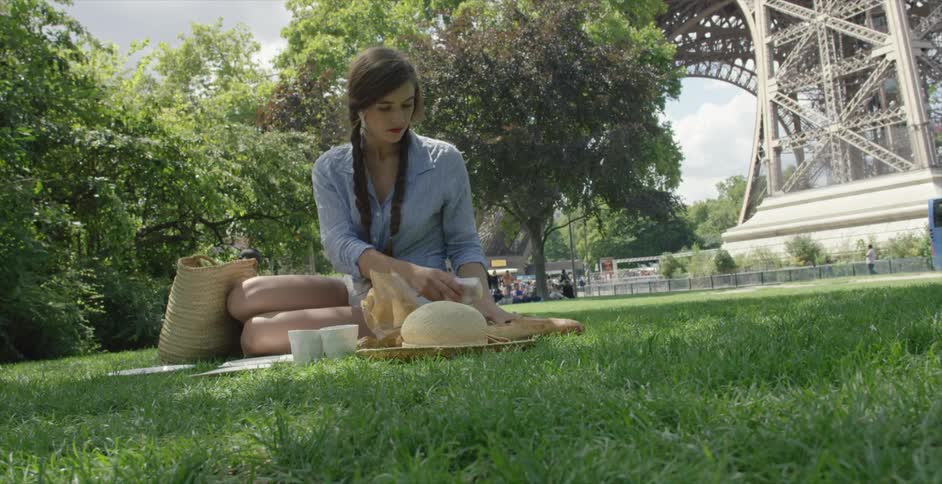 A woman preparing to picnic next to the eiffel tower