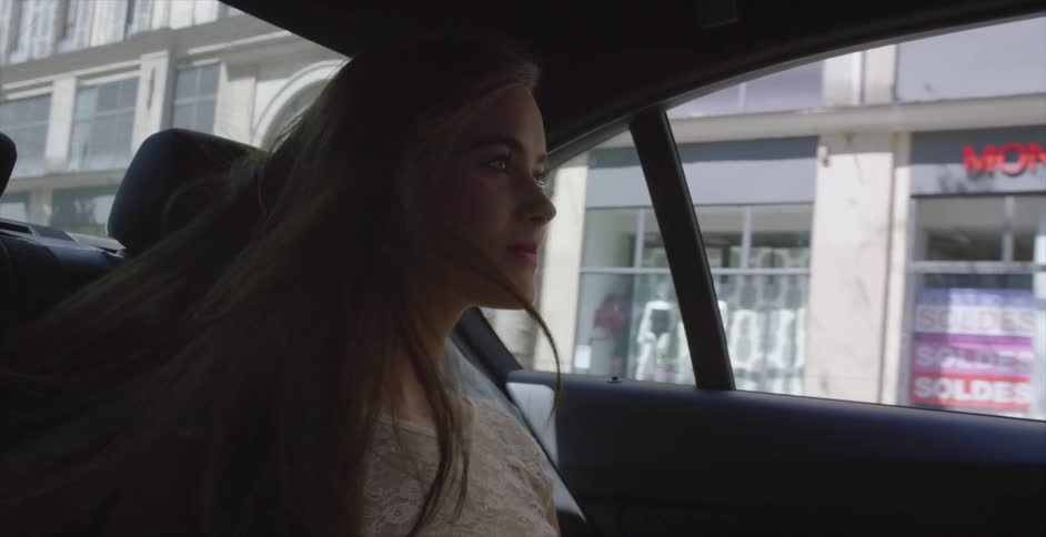 Woman riding in the back of vehicle looking out at the city