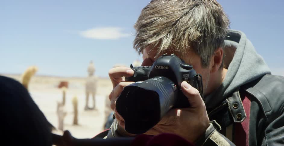 A photographer takes photos as children play in a rural area behind him
