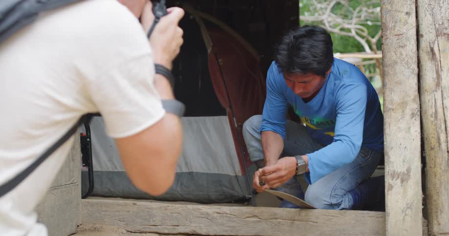 Hispanic man uses a scraper while a caucasian man photographs him