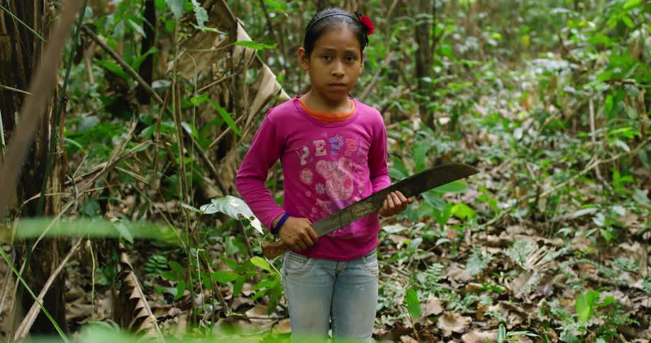 Girl stands in the forest holding a machete