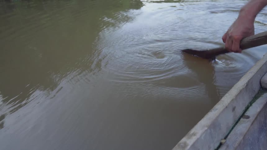 A person is rowing the boat in the muddy waters